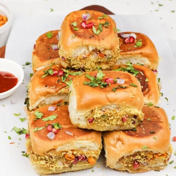 kachchhi dabeli served on a tray garnished with cilantro leaves, sev, peanuts and pomegranate seeds.