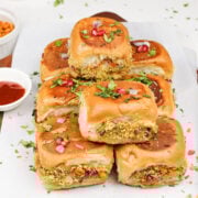 kachchhi dabeli served on a tray garnished with cilantro leaves, sev, peanuts and pomegranate seeds.