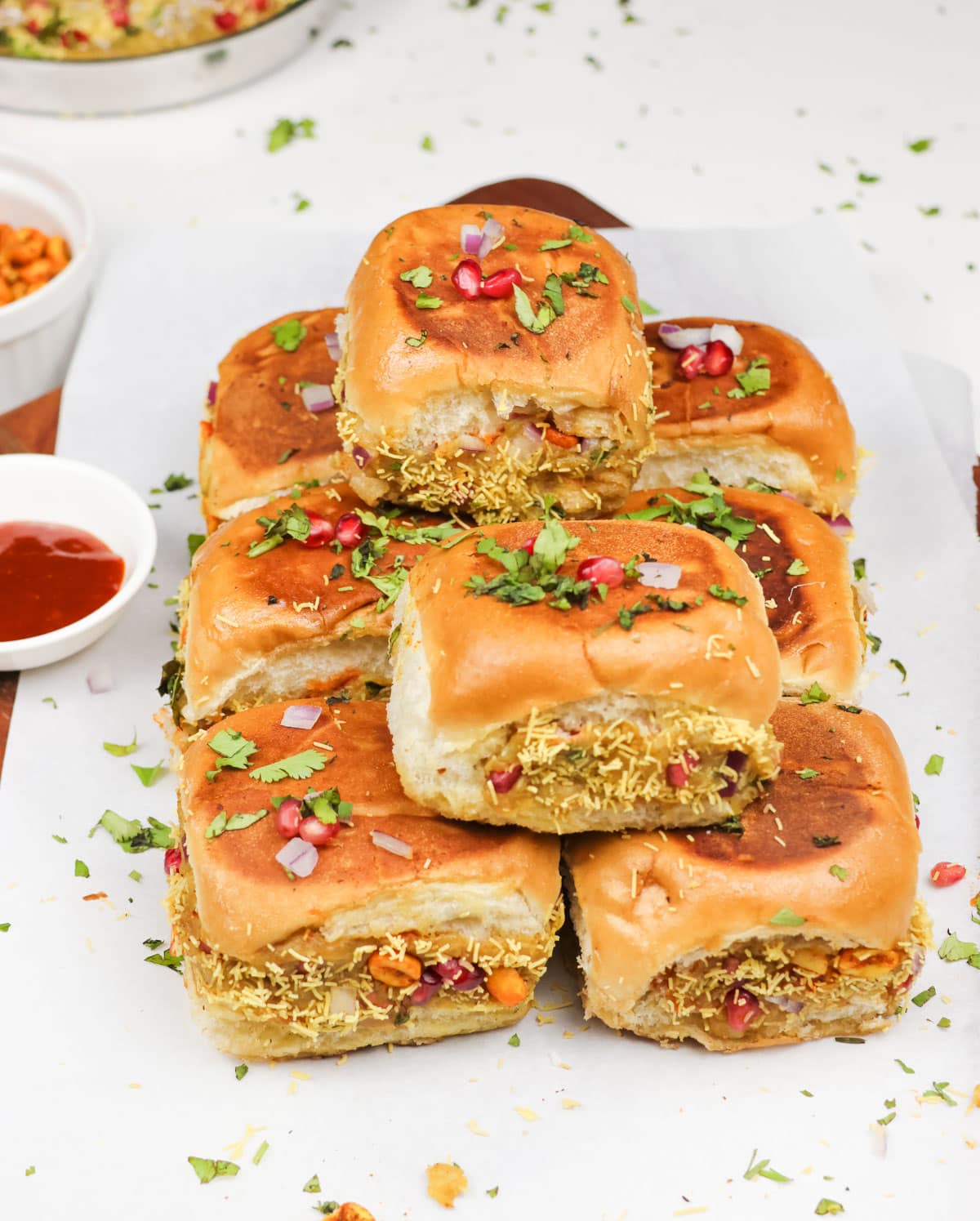 kachchhi dabeli served on a tray garnished with cilantro leaves, sev, peanuts and pomegranate seeds.