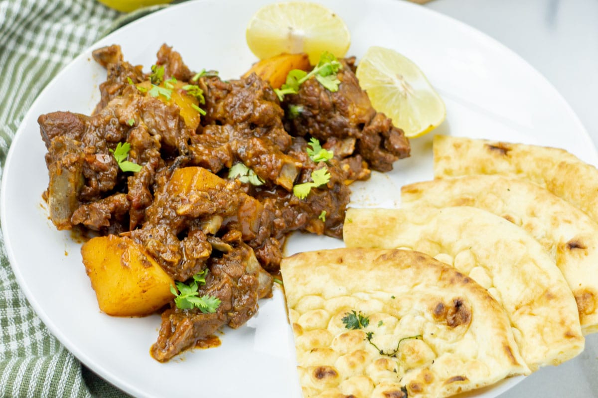 Lamb potato curry served alongside warm naan bread.