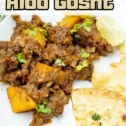 Aloo Gosht curry, adorned with vibrant cilantro leaves and served with naan.