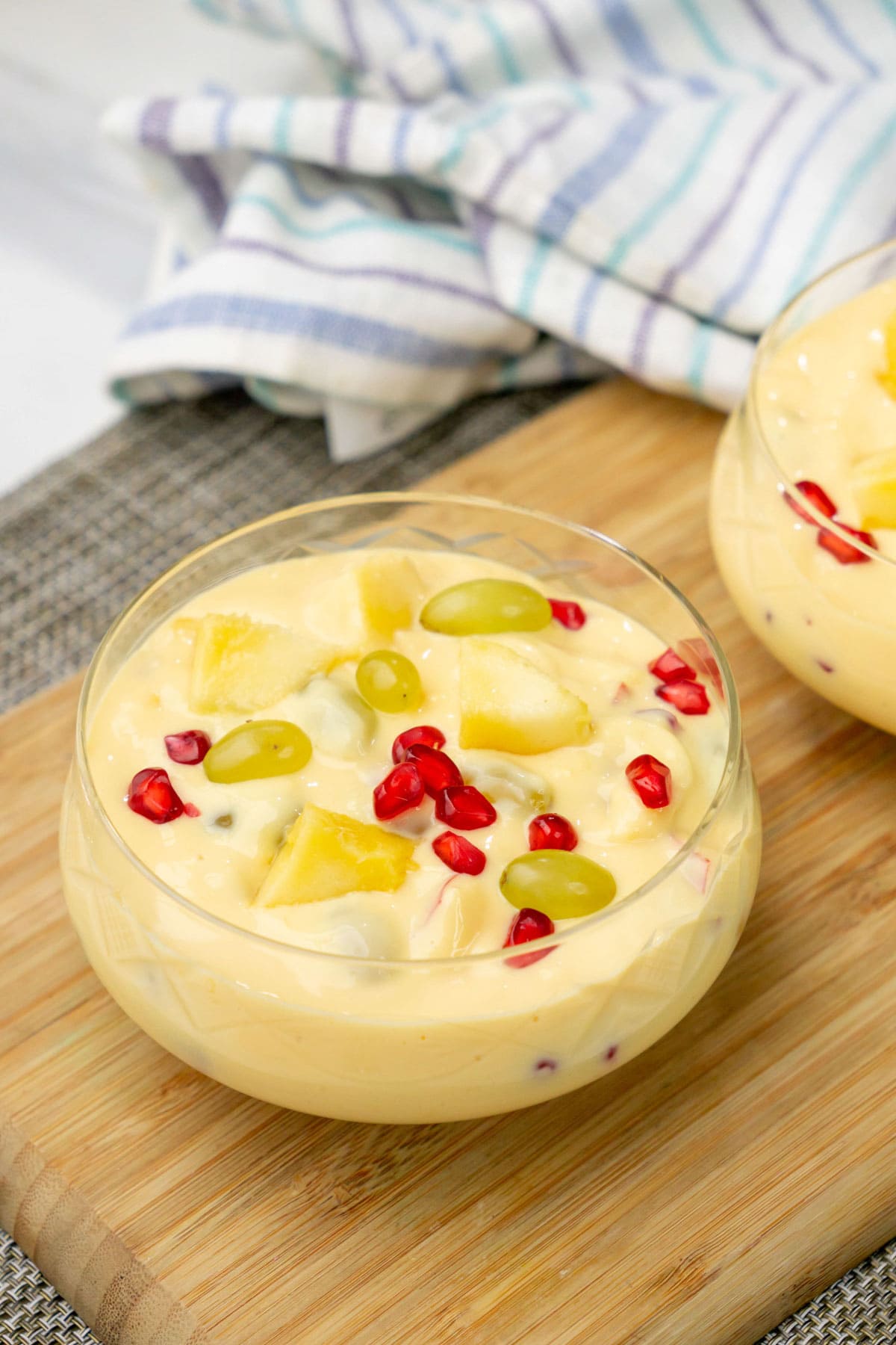 Fruit custard made with milk and brown and polson custard powder served in a glass bowl.