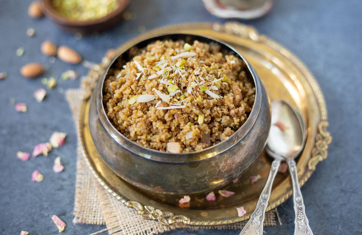 Gujarati Lapsi served in a silver bowl garnished with sliced nuts.