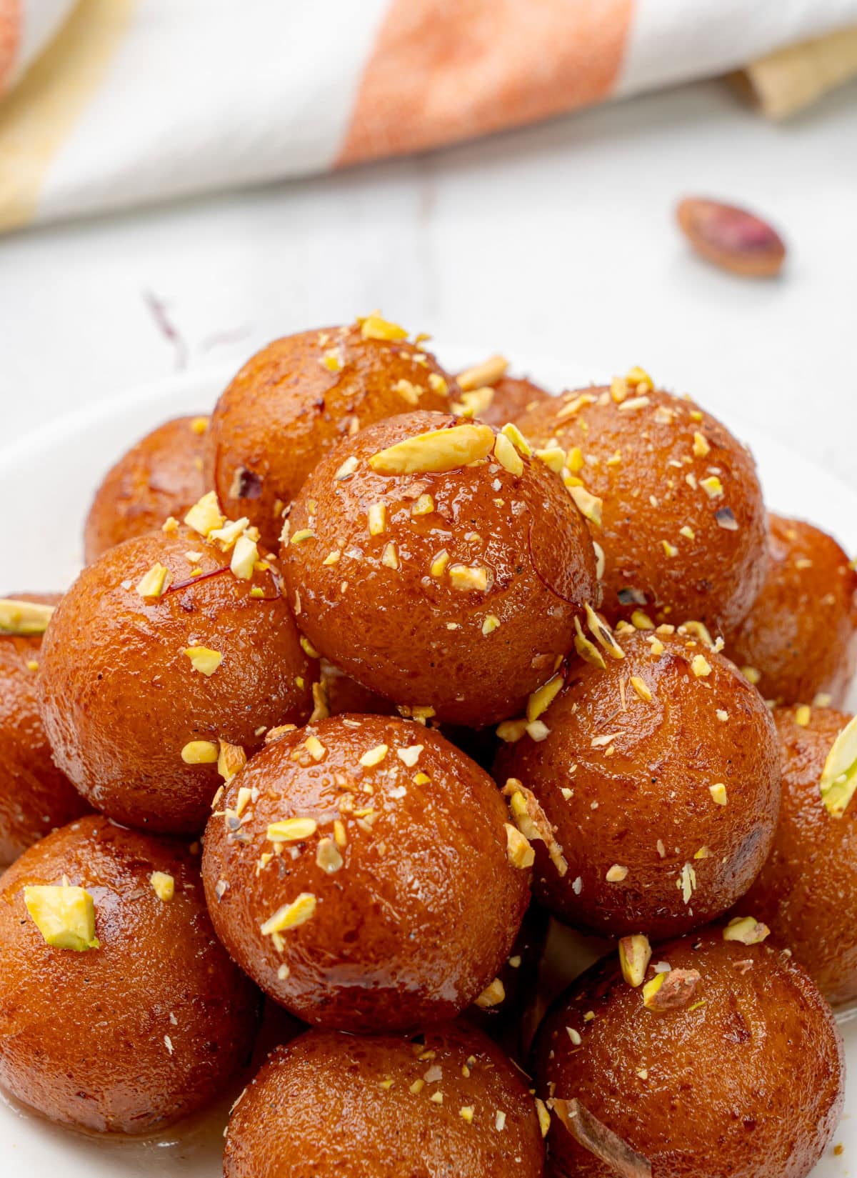 A stack of gulab jamuns served garnished with nuts.