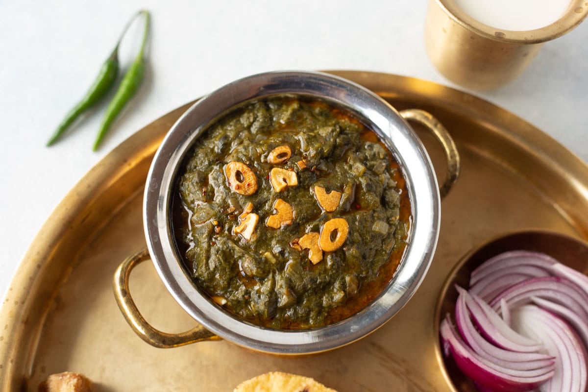 Authentic punjabi saag in a bowl on a brass plate.