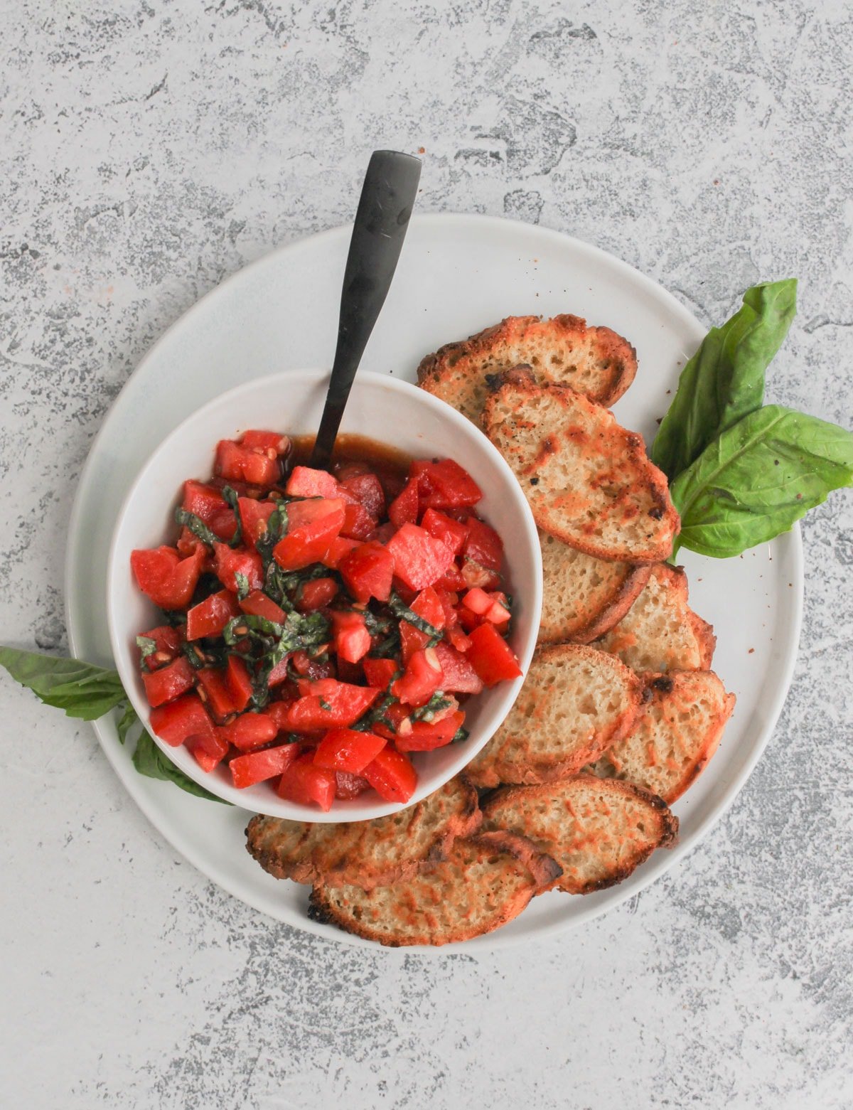 Top view of bruschetta dip in a bowl with toasted French bread