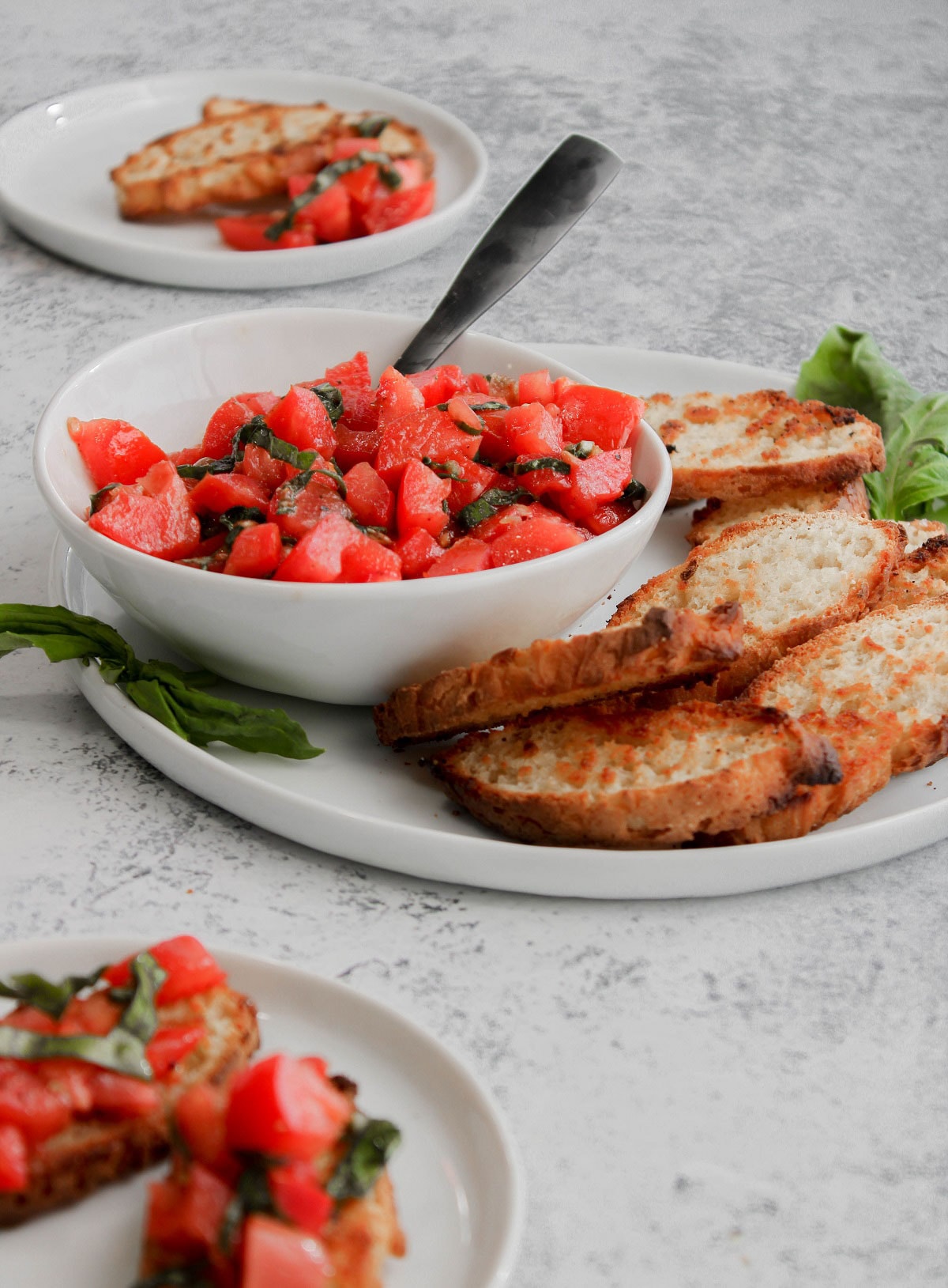 A bowl of balsamic tomato bruschetta being served with slices of toasted gluten-free bread.