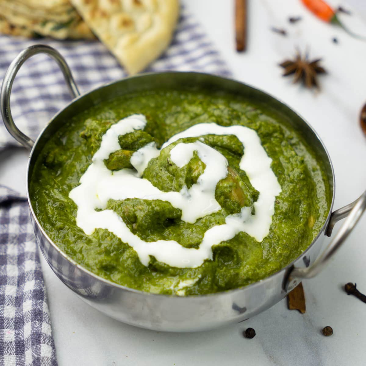 Chicken Saag in a bowl topped with cream.