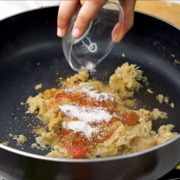 Spices added on top of sauteed onions in a pan.