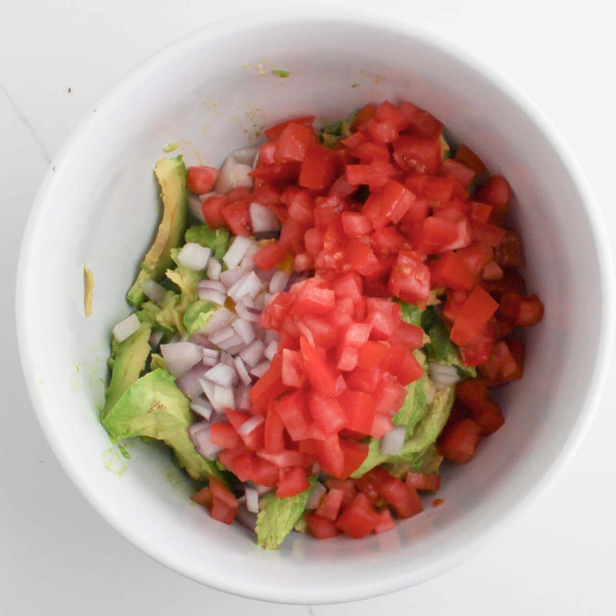 added sliced tomato in a bowl for Chunky Guacamole