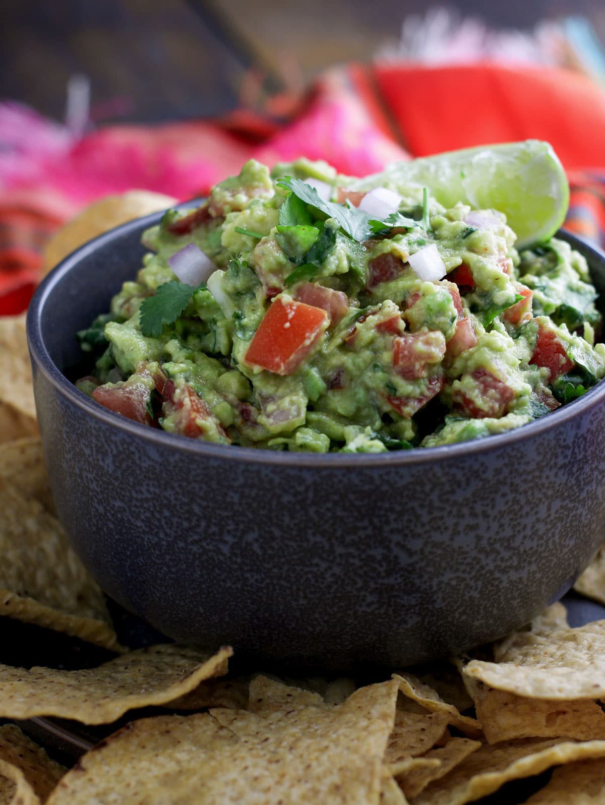 Close up shot of Chunky Spicy Guacamole in a bowl with some chips on side