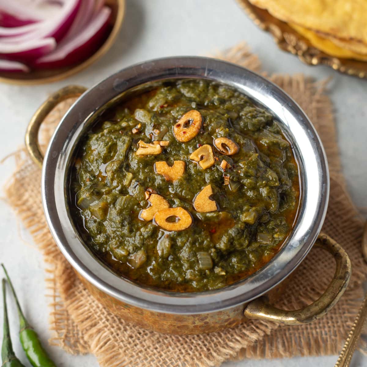 Sarson ka Saag served in a bowl topped with a tempering of ghee and garlic.