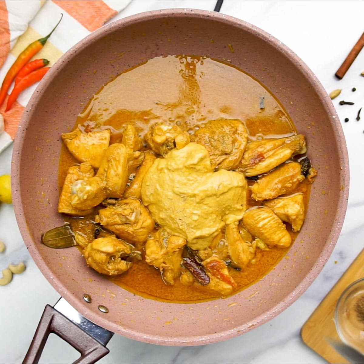 Cashew Onion Paste added to chicken being cooked in a pan. 
