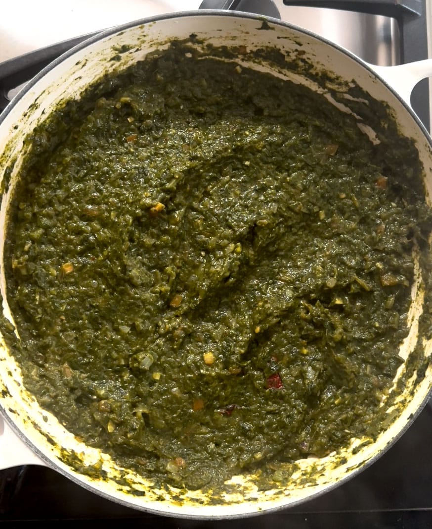 Punjabi Saag prepared in a large white pan. 