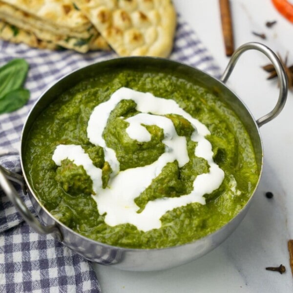 Saag Chicken in a bowl topped with cream.