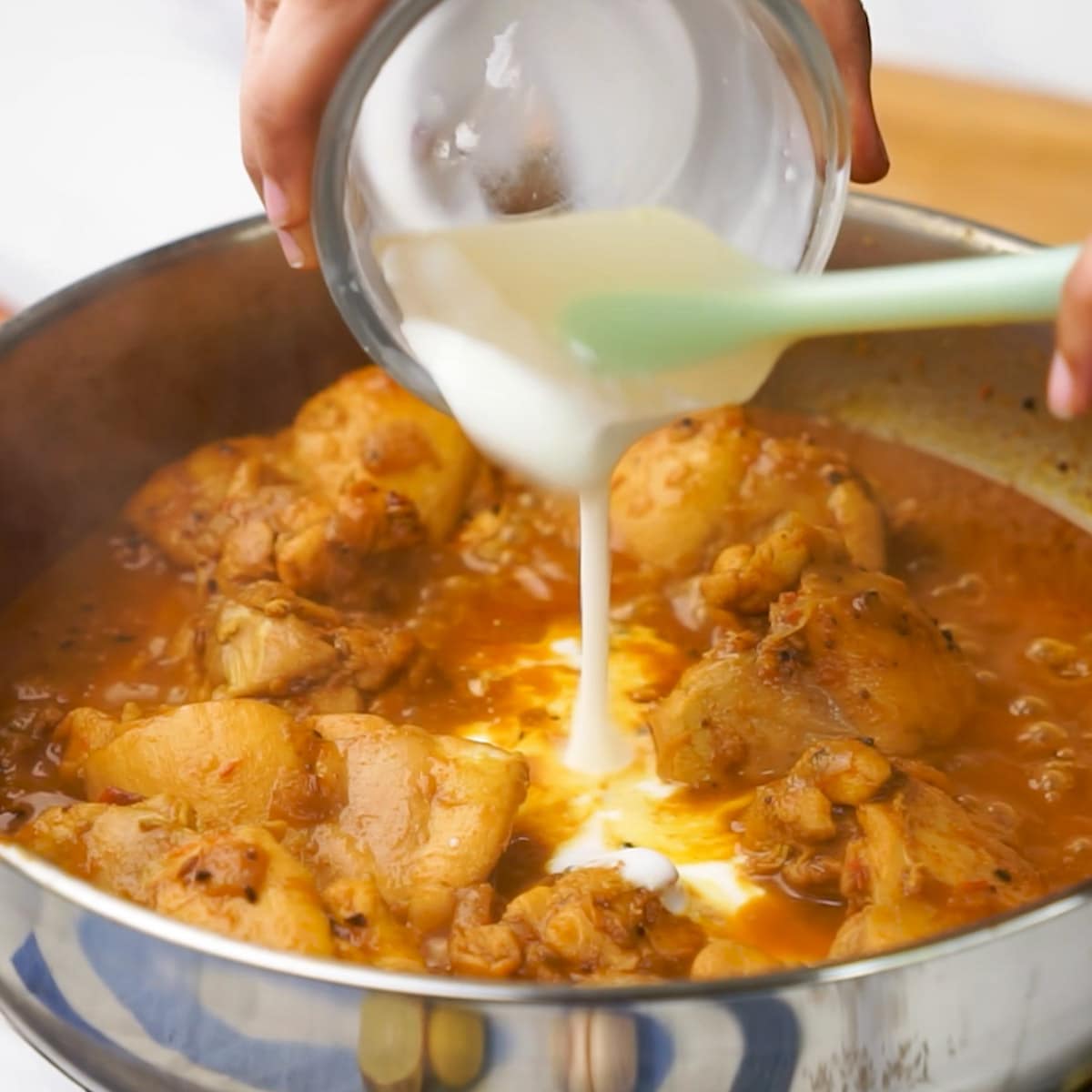Adding Yoghurt in the kadai filled with Achari Chicken