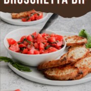 A bowl of bruschetta dip being served with slices of toasted bread.