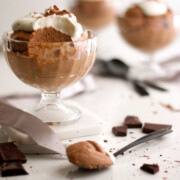 Chocolate mousse in a glass serving dish with whipped cream and shaved chocolate.
