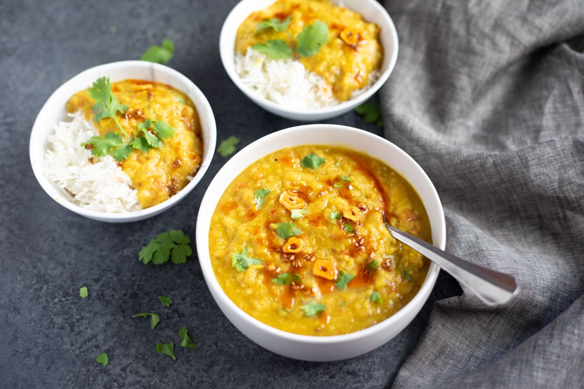 Two bowls of red lentil masoor dal with rice and another bowl of red lentil masoor dal