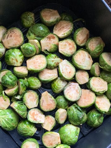 Seasoned halved brussels sprouts in the air fryer basket
