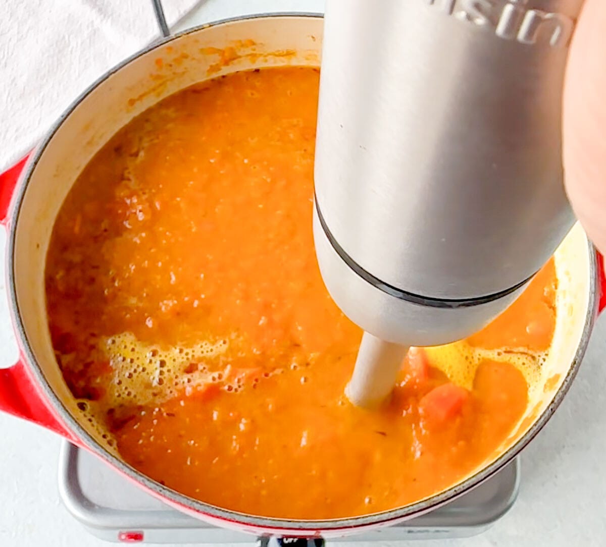 Blending the Pumpkin Carrot Soup with an immersion blender.