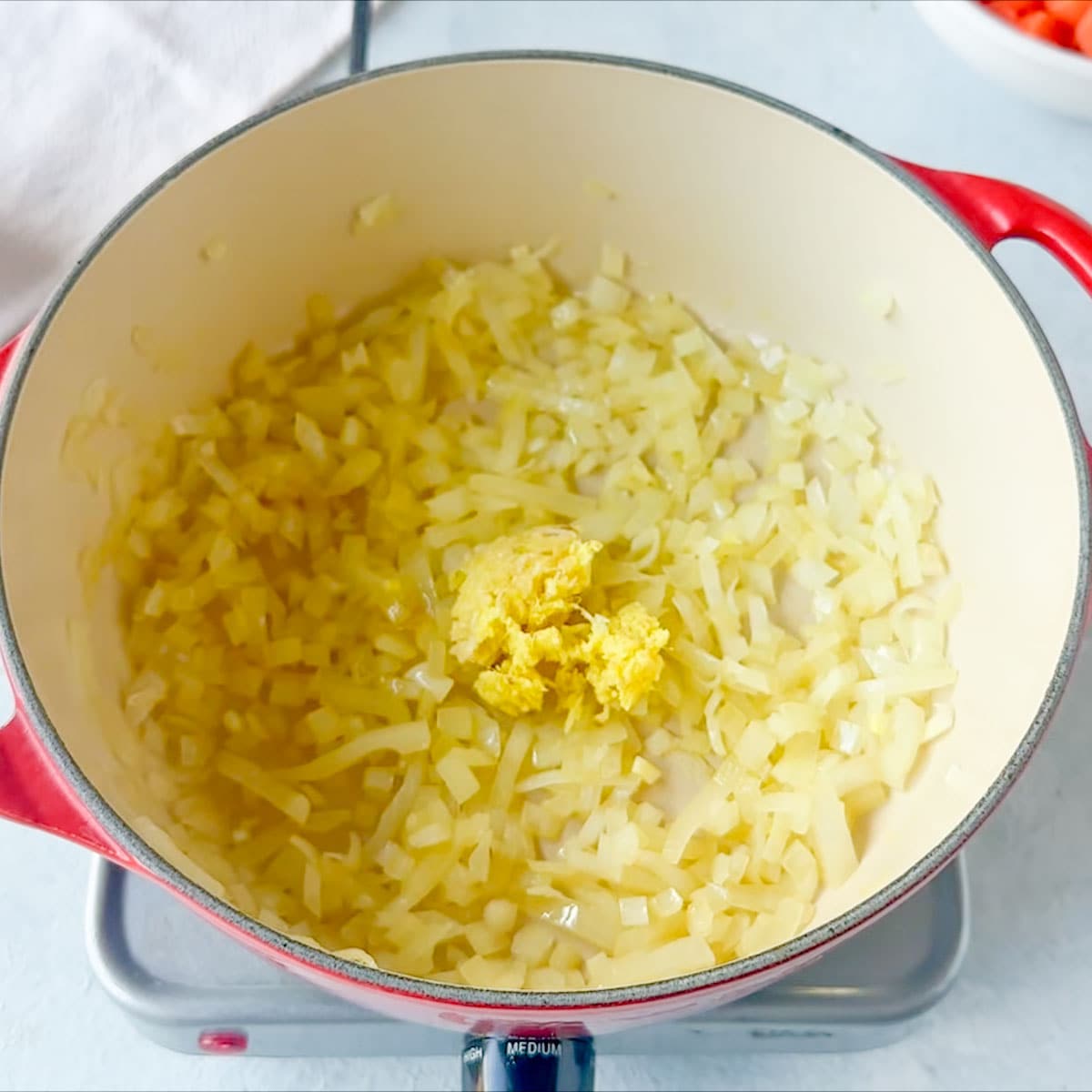 Adding the ginger in the pan filled with yellow onions