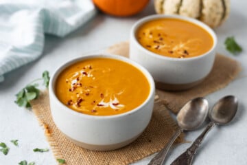 Pumpkin Carrot Soup ready to serve and decorated with Red chili flakes and black pepper along with cream