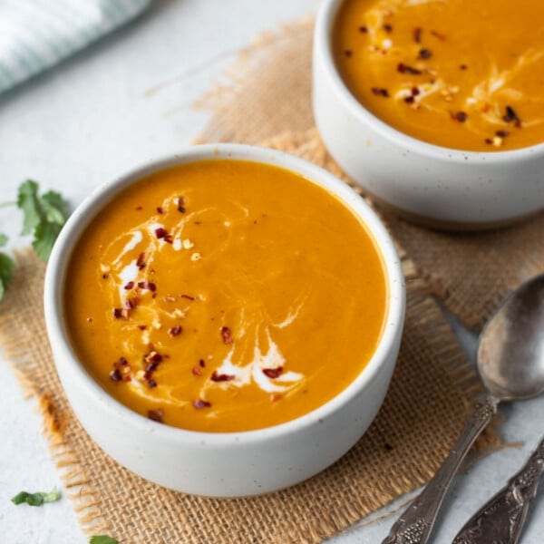 Pumpkin Carrot Soup served in bowls garnished with red chili flakes