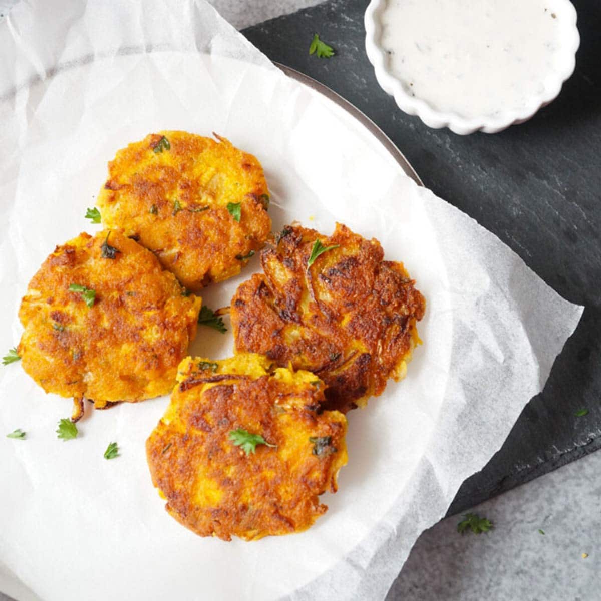 Vegan Chickpea Squash Fritters in a plate with yogurt dip on the side