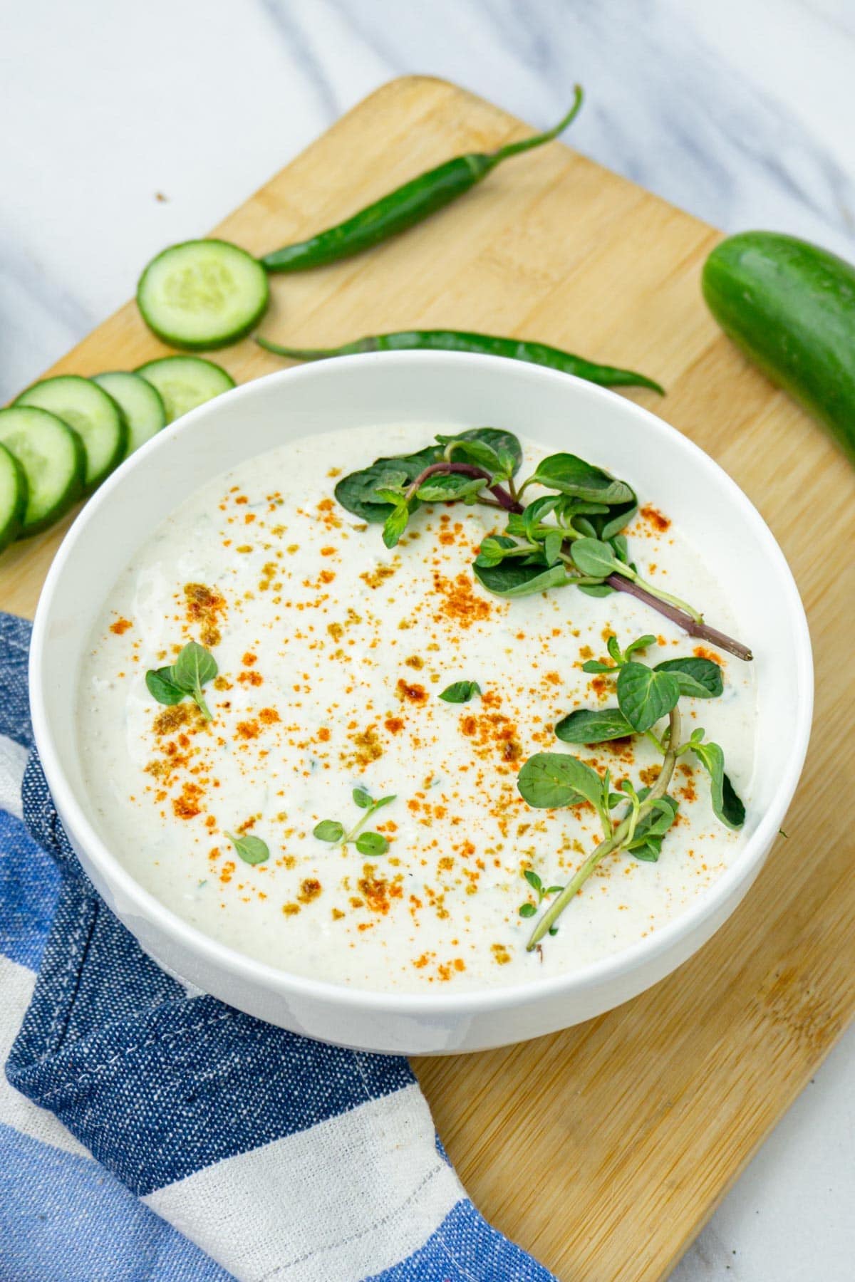 Cucumber Raita in a bowl garnished with mint leaves and spices