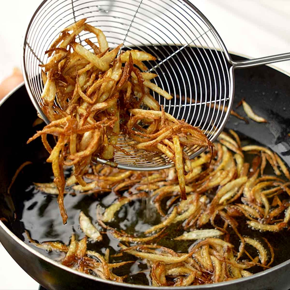 scooping out fried onions using strainer