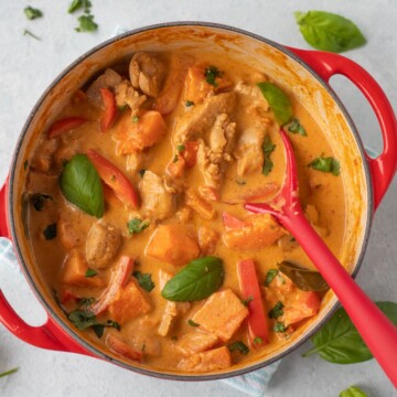 Pumpkin chicken curry cooked in a red Dutch oven.