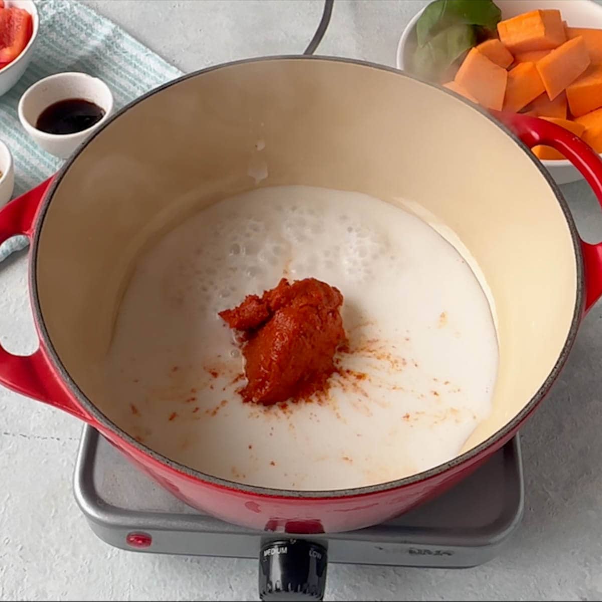 Red Curry Paste added to dutch oven over coconut milk.