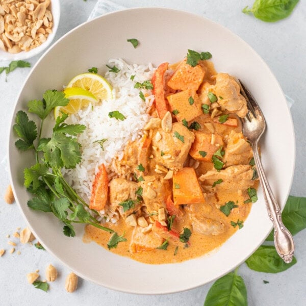 Pumpkin Chicken Curry in bowl with coconut milk, spices and cilantro leaves spread over