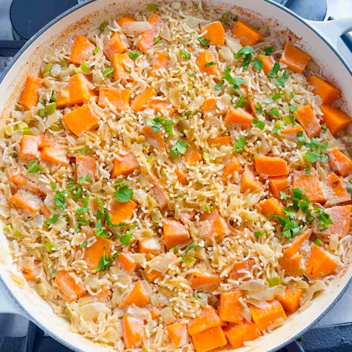 cooked pumpkin rice in a pan garnished with cilantro