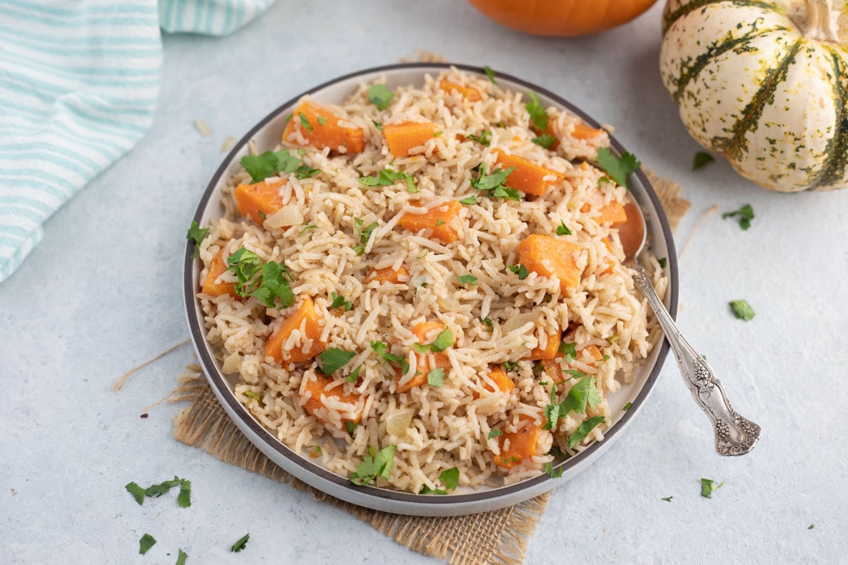 pumpkin rice in a plate with spoon garnished with cilantro