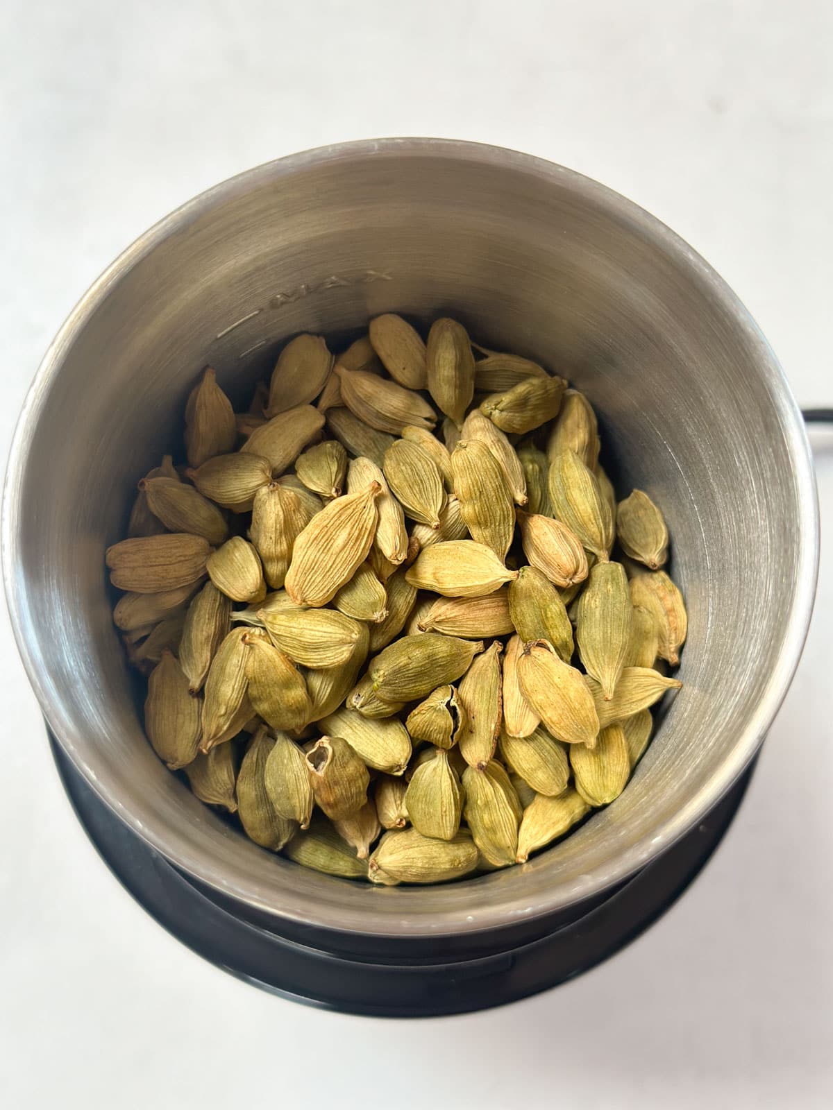 Green Cardamom pods in a spice grinder ready to grind