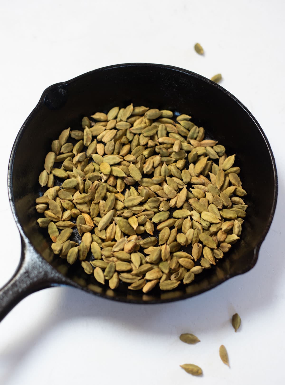 cardamom seeds in a iron skillet
