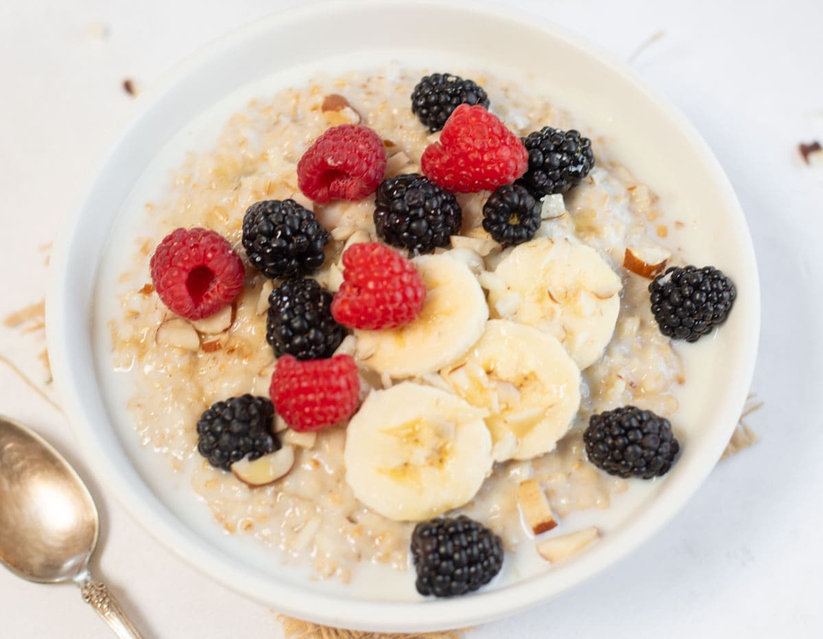 close-up shot of steel cut oats with slices of banana, berries and nuts as a toppings