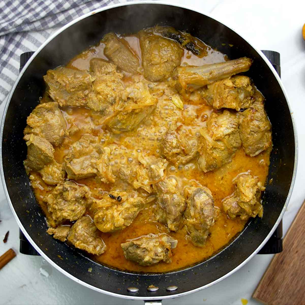 Cooking marinated mutton pieces in a pan with spices for the biryani.