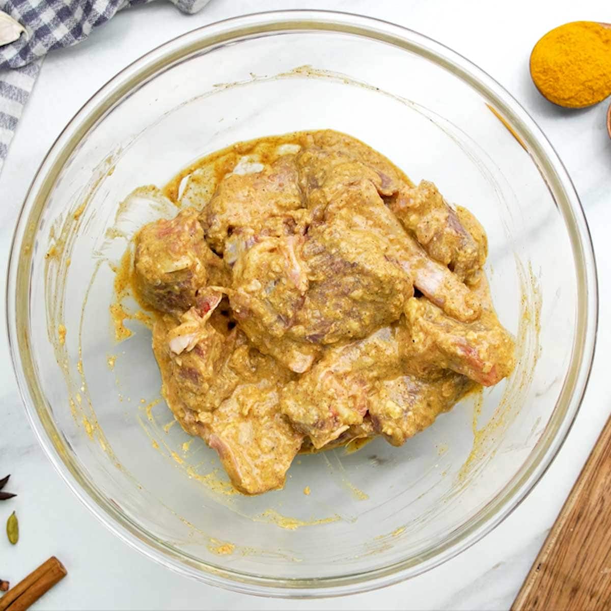 Mutton pieces marinating in a creamy yogurt sauce with ginger, garlic, chili powder, and other spices.