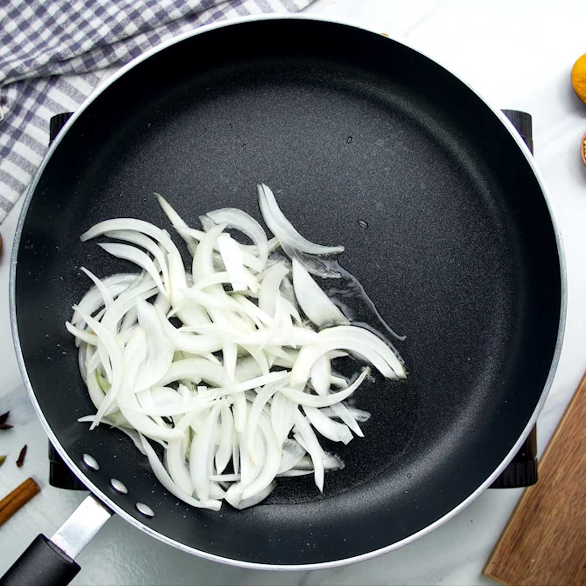 Sliced onions being fried in a pan until golden brown.