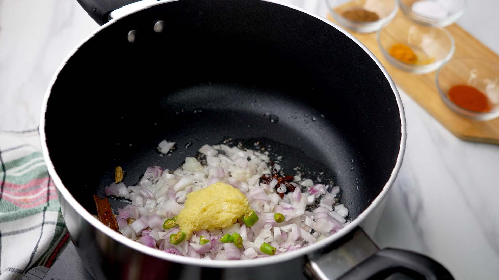 Add finely chopped onions, green chilies, and ginger garlic paste. Sauté until onions turn translucent.
