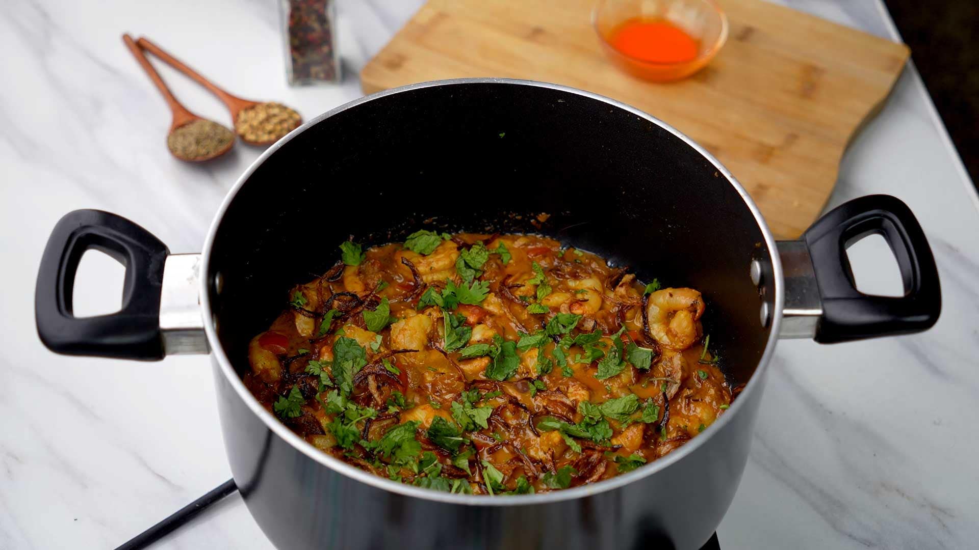 Shrimp biryani in a pan garnished with cilantro