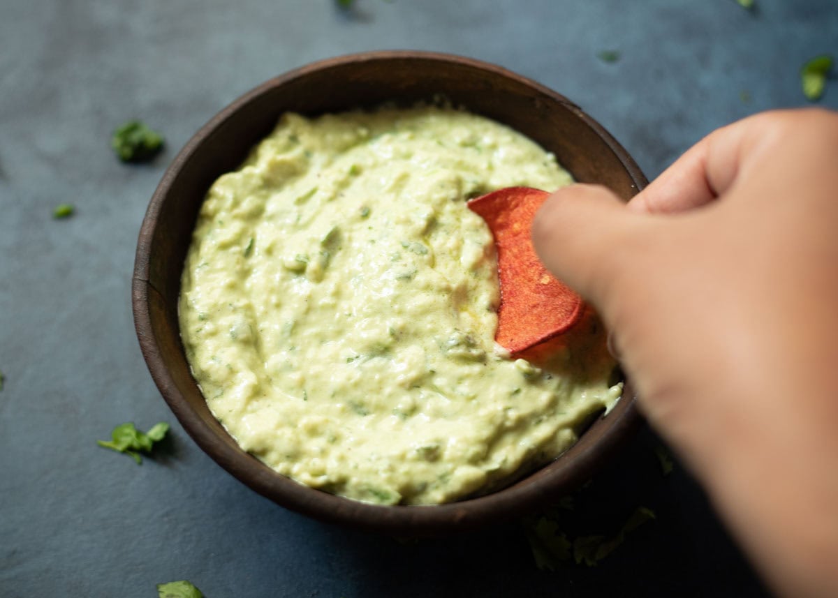 dipping a chip in a avocado cilantro dip