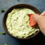 dipping a chip in creamy avocado cilantro sauce