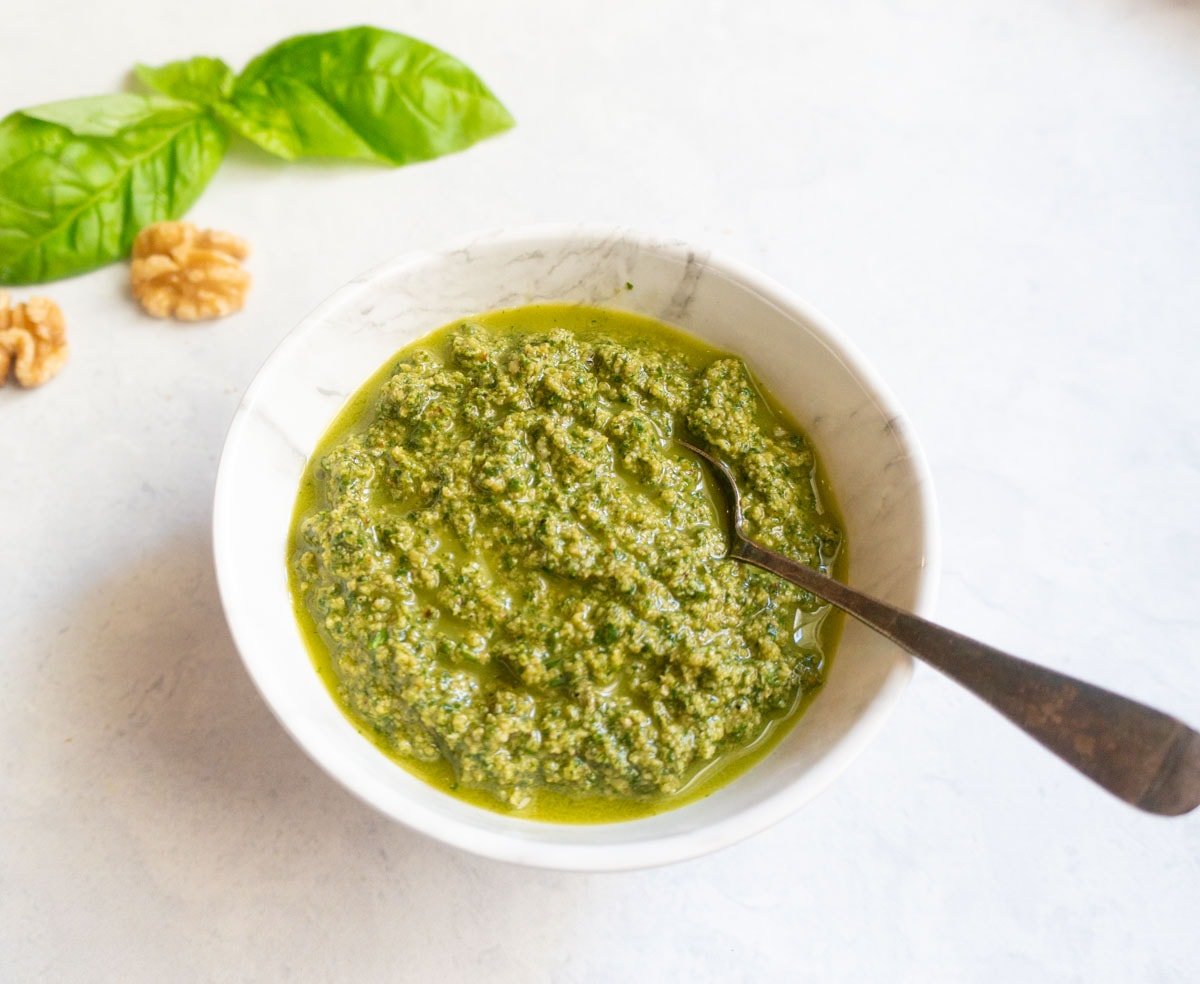 homemade Basil Walnut Pesto in a white bowl with spoon