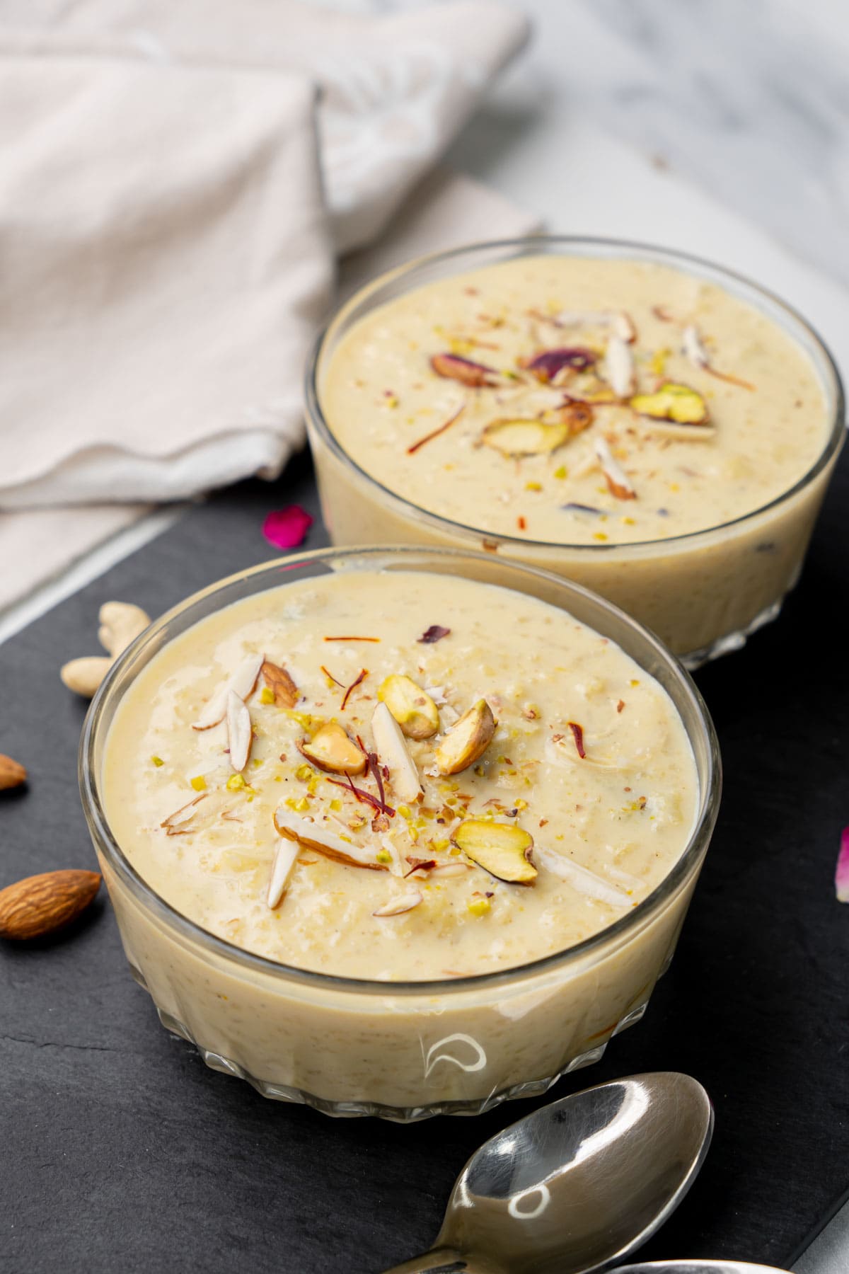 Rice kheer served in two bowls garnished with nuts. 