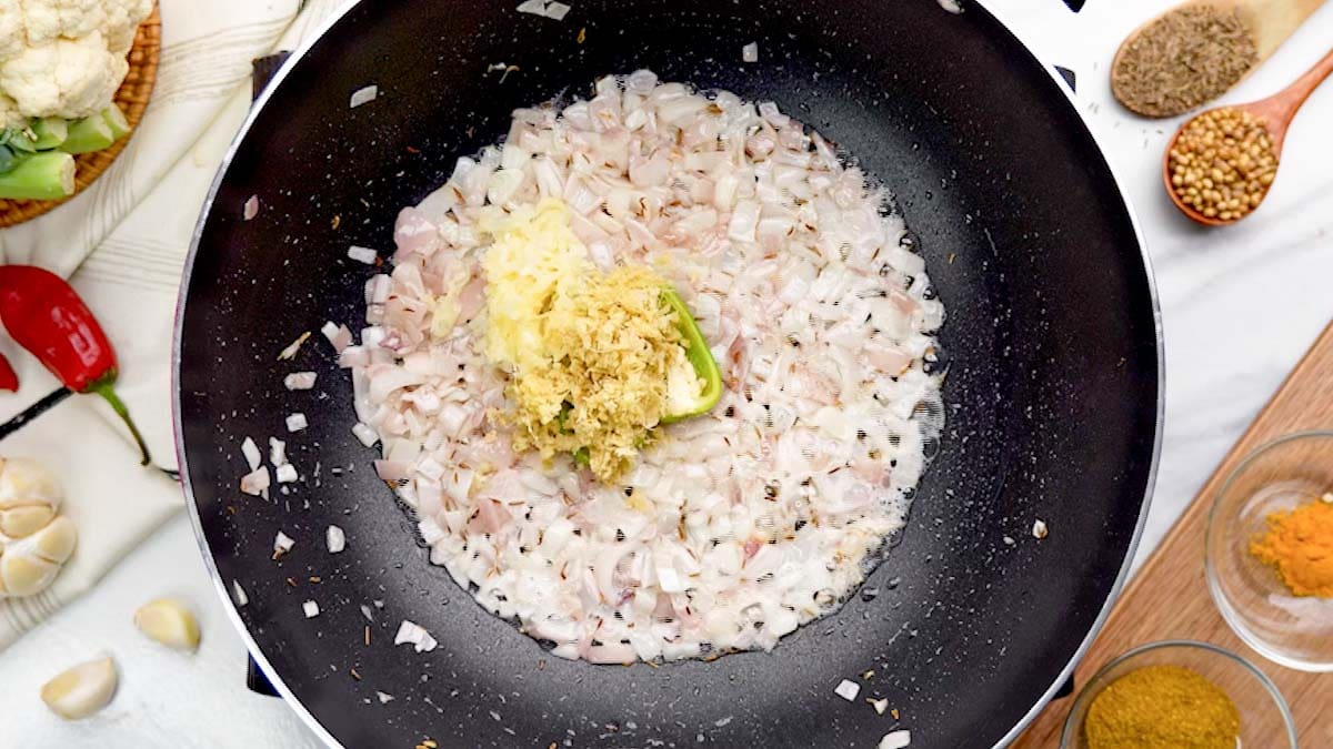 Add finely chopped green chili, minced ginger, and minced garlic to the pan.