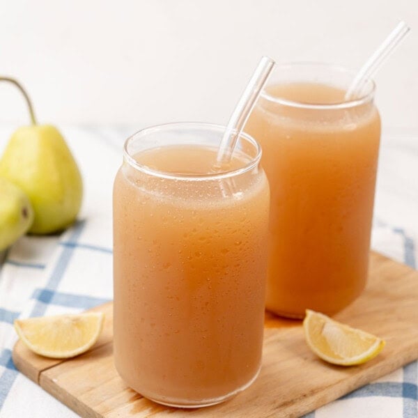 A glass of chilled pear juice, surrounded by whole pears